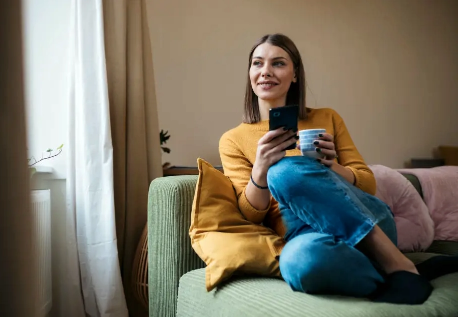 A woman using a phone while sitting on a couch